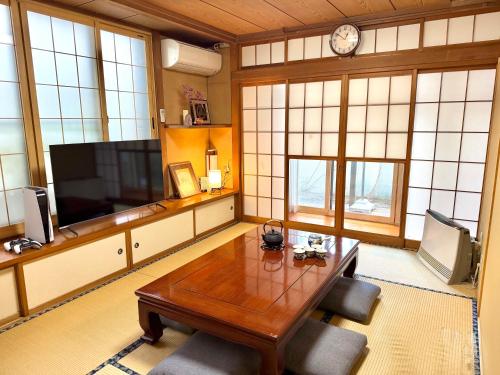 a living room with a wooden table and a tv at 松本城下一棟貸埋橋 in Matsumoto