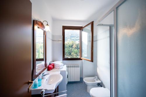 un bagno con lavandino e servizi igienici e due finestre di Italian Vacation Homes Unit2B Iseo Lake a Tavernola Bergamasca