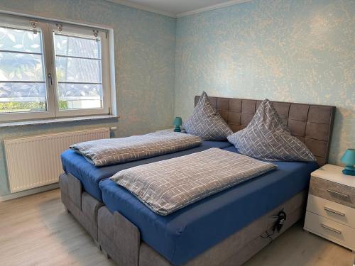 a bedroom with two beds with blue sheets and a window at Ferienwohnung Lena in Morbach