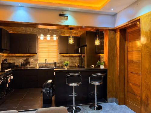 une cuisine avec des armoires noires et des tabourets de bar dans l'établissement Bhai Apartments, à Mwanza