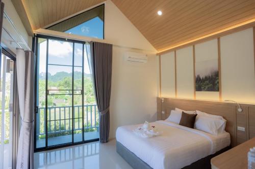 een slaapkamer met een bed en een groot raam bij Annrin cafe & Resort in Ban Song Phi Nong