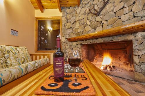 een fles wijn op een tafel in een woonkamer met open haard bij Melewe Moquehue in Moquehue