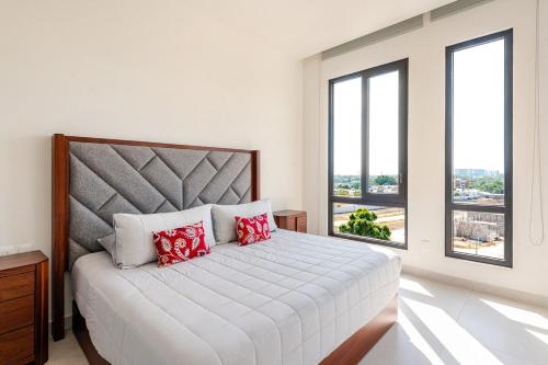 a white bedroom with a large bed with red pillows at Luxury Condo en Nuevo Vallarta Alberca Tipo Resort in Nuevo Vallarta