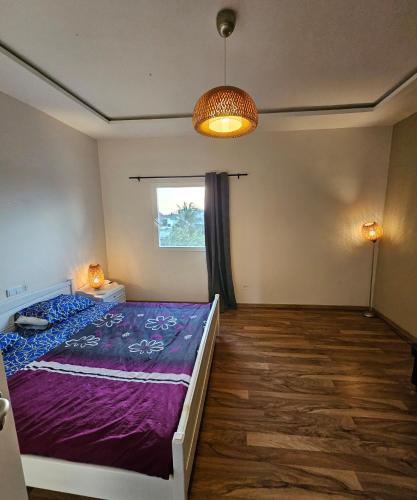 a bedroom with a purple bed and a window at Appartement blue sky unique et élégante in Lomé