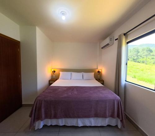 een slaapkamer met een groot bed en een raam bij Brisa Mar e Cachoeira in Governador Celso Ramos