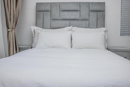 ein großes weißes Bett mit weißen Kissen im Schlafzimmer in der Unterkunft Luxury 1 Bed Apartment in Sandton