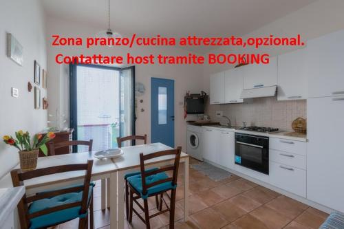 een keuken met witte kasten en een tafel en stoelen bij Casa di Sale - Chianalea in Scilla