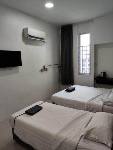 a hotel room with two beds and a flat screen tv at comfortpahlawan in Sibu