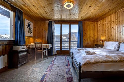 a bedroom with a bed and a desk and a window at Chalet Fauvette in La Tzoumaz