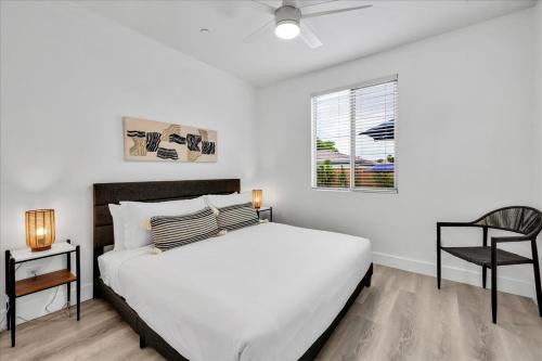 a white bedroom with a bed and a chair at Oh la la Coachella in Coachella