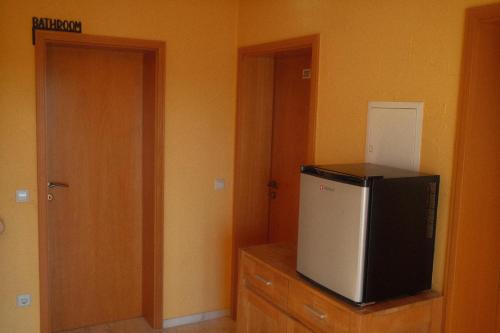 een kamer met een kleine koelkast en een deur bij Pension Zum Waldrand in Sinsheim