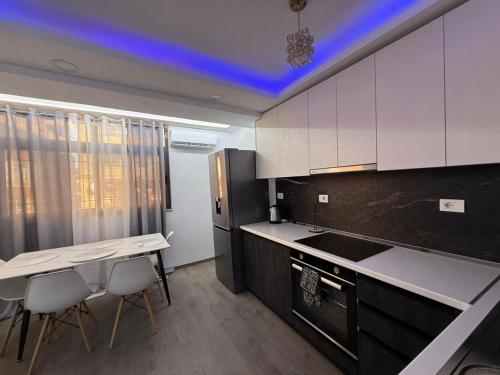 een keuken met witte kasten en een tafel en stoelen bij Shkodra Apartment AR in Shkodër