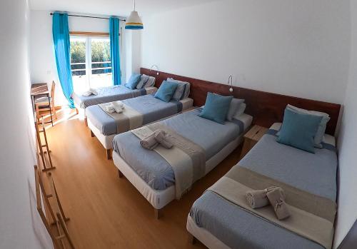 Zimmer mit 4 Betten und blauen Kissen in der Unterkunft Wellnesshouse in Atouguia da Baleia