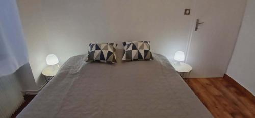 a large bed with two pillows on top of it at Entre sel et vignes in Lons-le-Saunier