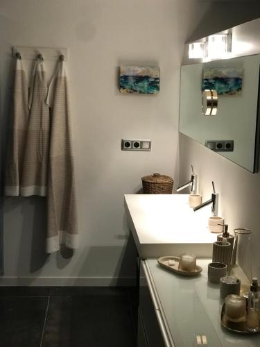 een badkamer met een witte wastafel en een spiegel bij C'est la vie! in L'Escala