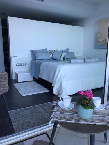 een slaapkamer met een groot bed en een tafel met bloemen bij C'est la vie! in L'Escala