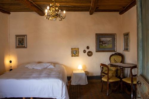 ein Schlafzimmer mit einem Bett, einem Tisch und einem Kronleuchter in der Unterkunft Cascina Zan in Paroldo