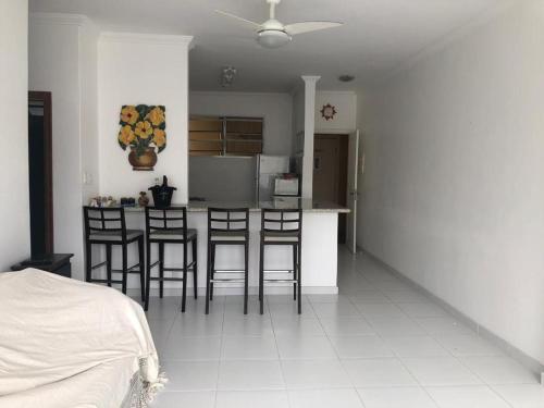 une cuisine avec un comptoir et des tabourets dans une pièce dans l'établissement Pitangueiras Apartment, great location, oceanfront, à Guarujá