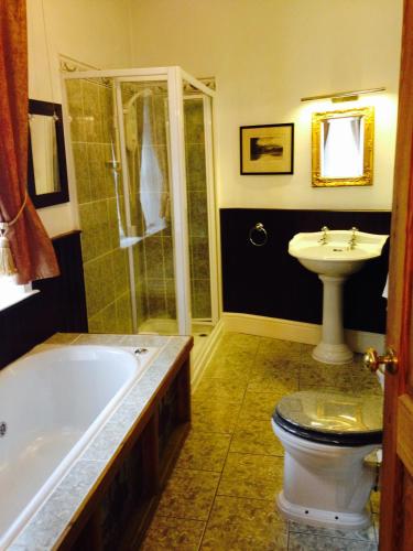 a bathroom with a tub and a toilet and a sink at The Old Registry guest house in Haworth