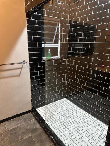 a bathroom with a black tiled shower with a window at Bell rose oaks guest house in Blomtuin