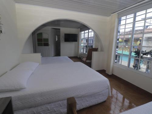 een slaapkamer met twee bedden en een groot raam bij Hotel Alcalá in Alcalá