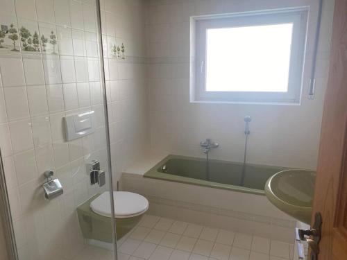 a bathroom with a tub and a toilet and a sink at Ferienhaus Wolfurt in Wolfurt