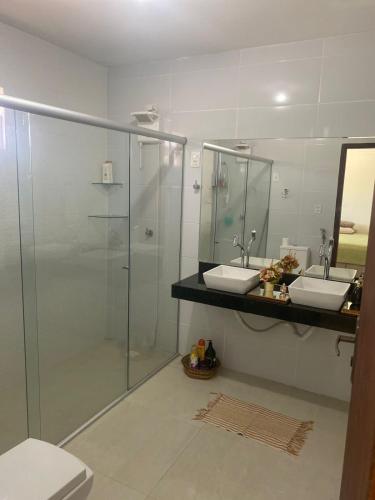 een badkamer met twee wastafels en een glazen douche bij Casa Campos do Mar in Conde