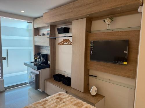 a living room with a flat screen tv and a kitchen at Tiny Spot in Ocaña