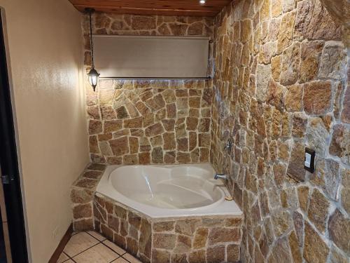 a bath tub in a room with a stone wall at Hotel Cibeles Resort in Heredia