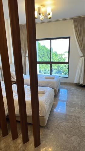 trois lits dans une chambre avec une grande fenêtre dans l'établissement Mazaya VIP Stay, à Mawāliḩ