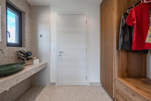 een badkamer met een glazen douchedeur en een wastafel bij Dina Villa in Roumelí