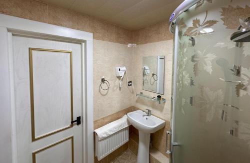 un bagno con lavandino, doccia e porta di Reikartz Namangan a Namangan