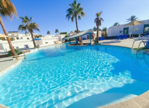 une grande piscine bleue avec des palmiers en arrière-plan dans l'établissement kanabesh hotel, à Charm el-Cheikh