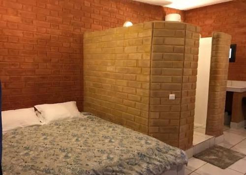 een bakstenen muur met een bed in een kamer bij HÔTEL Assinie LODGE in Assinie