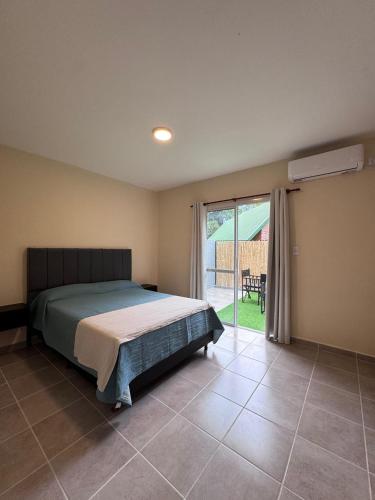 ein Schlafzimmer mit einem Bett und einer Glasschiebetür in der Unterkunft Las Moradas Ale in Villa Carlos Paz