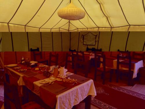 扎古拉Riad Perlamazigh的帐篷内的用餐室配有桌椅