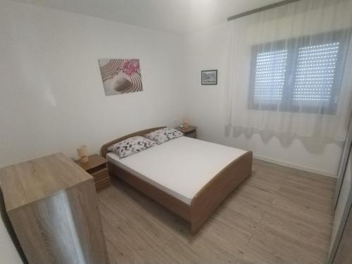 une chambre blanche avec un lit et une fenêtre dans l'établissement Apartman LAURA 1, à Ražanac