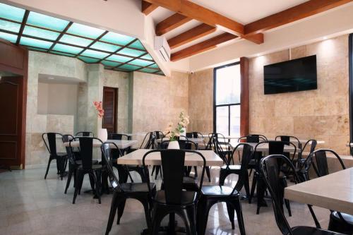 una sala con tavoli, sedie e TV a schermo piatto di Hotel Grand Lion a Torreón