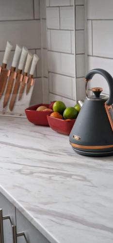 a tea kettle on a counter with a bowl of fruit at Contractors & Families Large Drive M1 M69 Wifi in Leicester