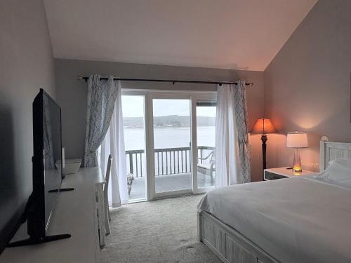 una camera da letto con un letto e una porta su un balcone di Riverfront Home with a View! a Groton
