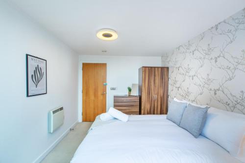 a bedroom with a large white bed with blue pillows at Modern Leeds Apartment Close to LGI & University in Central Station
