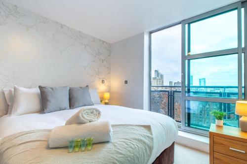 a bedroom with a white bed with a large window at Modern Leeds Apartment Close to LGI & University in Central Station