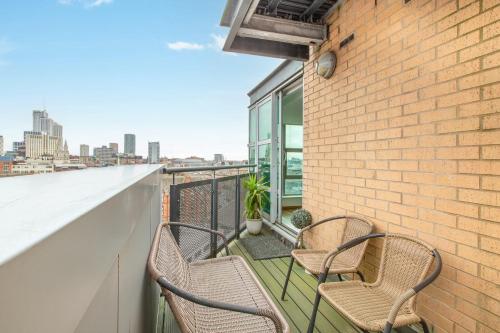 three chairs on a balcony with a view of the city at Modern Leeds Apartment Close to LGI & University in Central Station