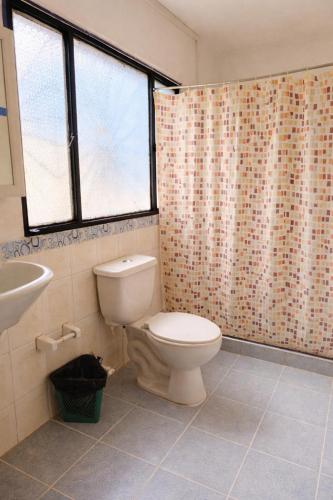 a bathroom with a toilet and a shower curtain at Hostal La Clarita in Fusagasuga
