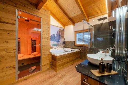 a bathroom with a tub and a sink and a shower at Orchidea Suite & SPA Apartments in Canazei