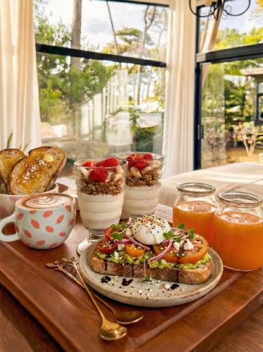 a table topped with a plate of food with a sandwich at Bella Bungalows in Punta Del Diablo