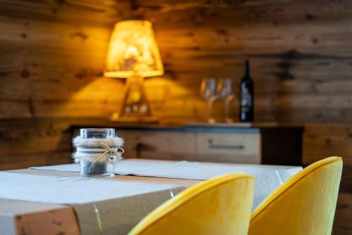 a table with yellow chairs and a table with a lamp at Orchidea Suite & SPA Apartments in Canazei