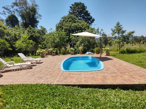 een zwembad met een parasol en stoelen en een patio bij Chacara do japonês 
