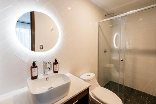 een witte badkamer met een wastafel en een spiegel bij Casa Castillo Condesa in Mexico-Stad