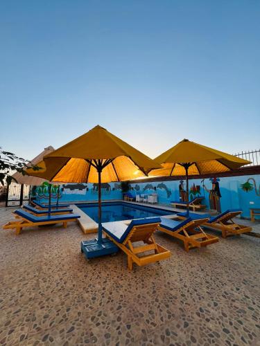 a group of lounge chairs and umbrellas on a beach at Horus Golden Luxor in Luxor